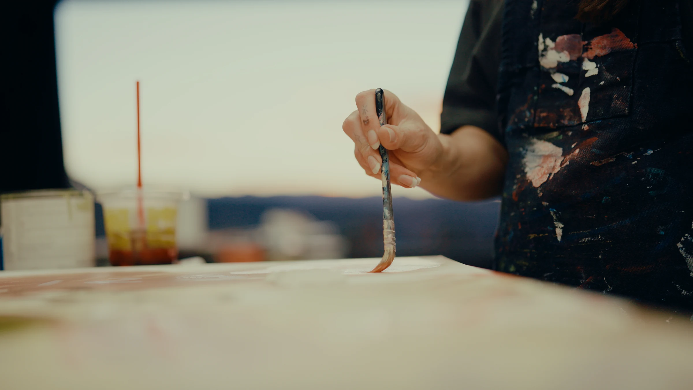 An artist's hand drawing a paintbrush across a canvas.