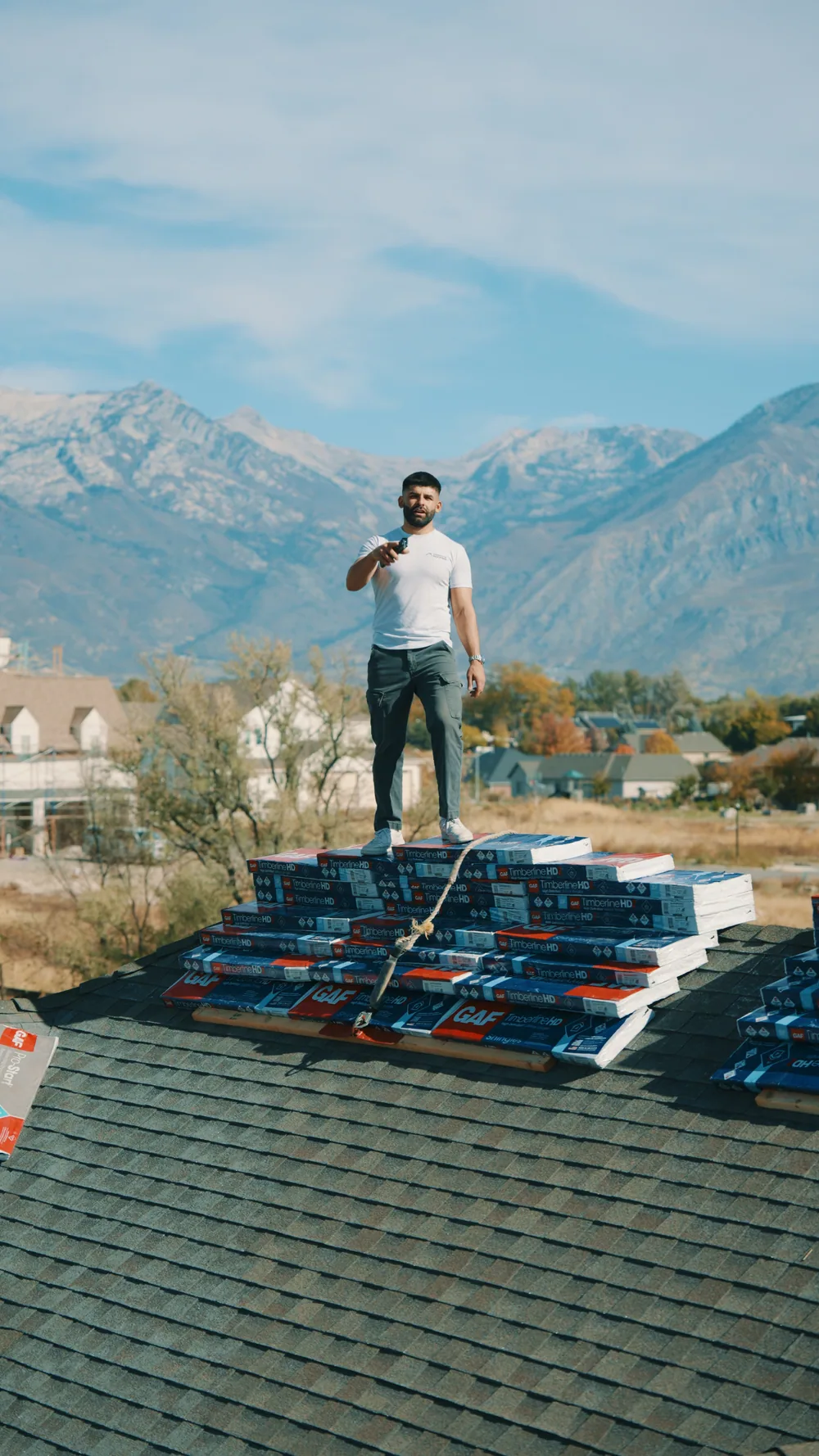 A roofer on a rooftop with mountains behind him.